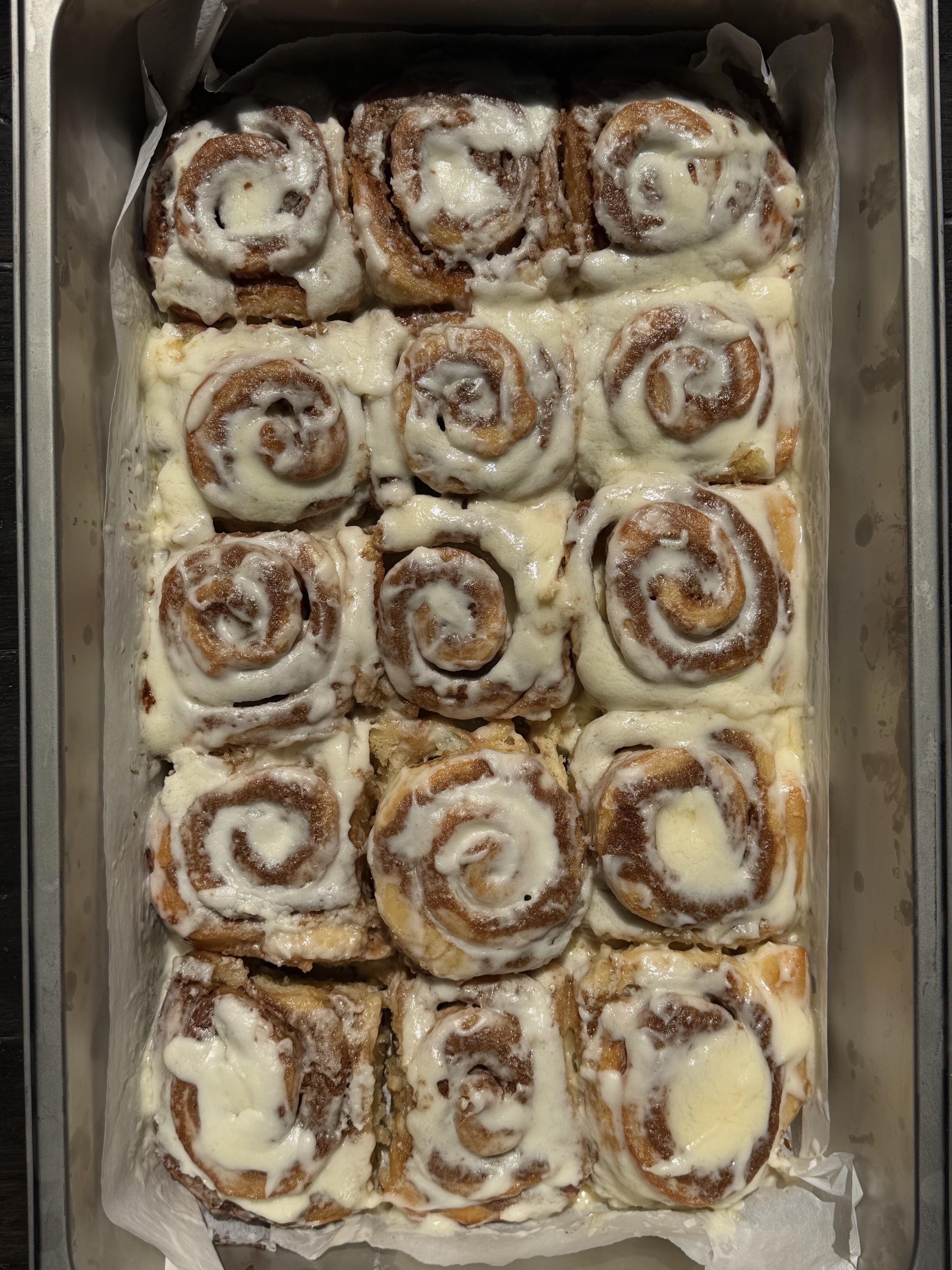 A tray of Berloom cinnamon rolls under cream cheese frosting